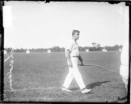 Archer H. B. Richardson holding a bow, walking on an archery field - Chicago Daily News, Inc.