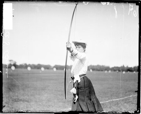 Archer Miss C. S. Bruce holding a bow and arrow and pulling back the bow string - Chicago Daily News, Inc.