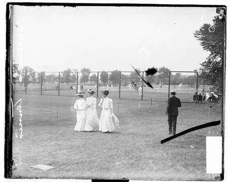 Three unidentified women walking in front of a tennis courts at Onwentsia Club - Chicago Daily News, Inc.