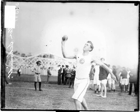 Walter Schmidt of Central Turner, throwing a shot put, standing on a dirt athletic field - Chicago Daily News, Inc.