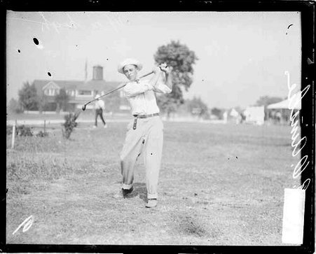 Golfer R. O. Ainslee holding a golf club over his shoulder in a follow-through position - Chicago Daily News, Inc.
