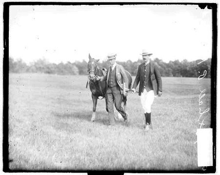 Polo player Foxhall P. Keene and an unidentified man walking with a horse on a field - Chicago Daily News, Inc.
