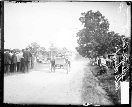 Automobile driver Wood driving an electric car on a road during the Algonquin Hill Climbing Contest - Chicago Daily News, Inc.