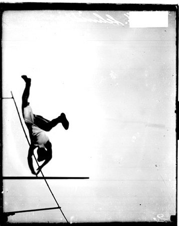 Pole vaulter W. M. Schmidt falling over a horizontal bar while performing a pole vault outdoors - Chicago Daily News, Inc.