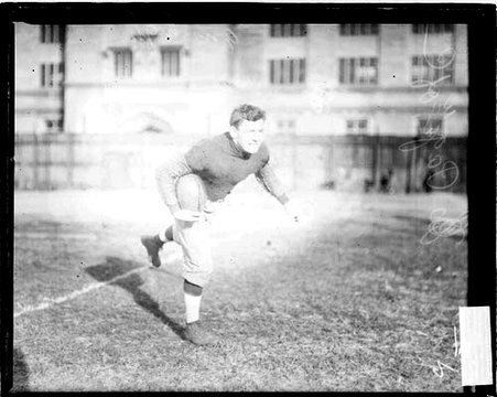 University of Chicago football player Orville Page holding a football, standing on one foot - Chicago Daily News, Inc.