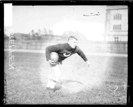 University of Chicago football player Walter Steffen holding a football, standing ready to run - Chicago Daily News, Inc.