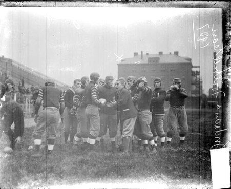 Ralph Hoagland speaking with a group of Indiana University football players on an athletic field at Marshall Field - Chicago Daily News, Inc.