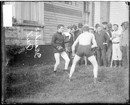 Pugilists Frankie Neil and Kid Sullivan standing in fighting stances while boxing on a lawn - Chicago Daily News, Inc.