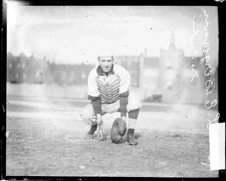 Catcher L. E. Bergersen of the DePaul University baseball team, holding his hands low to the ground - Chicago Daily News, Inc.