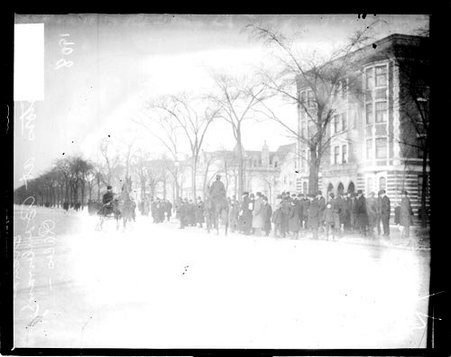 Horse harnessed to a carriage sled pulling the carriage on a snow-covered street - Chicago Daily News, Inc.