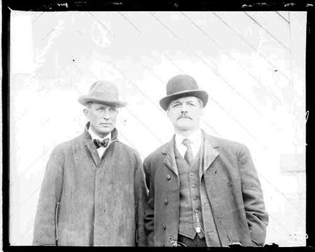 Horsemen Charles Dean and E. J. Rochon standing in front of a light-colored backdrop - Chicago Daily News, Inc.