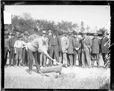 Pugilist Stanley Ketchel chopping a wooden log with an axe - Chicago Daily News, Inc.