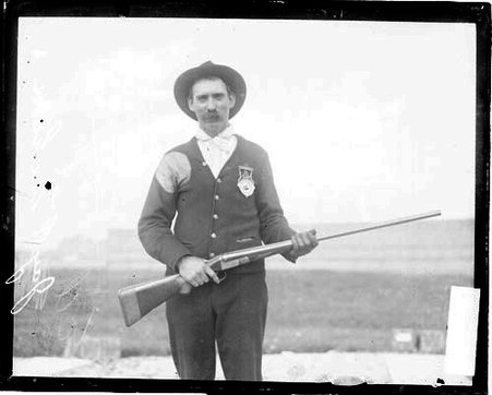Hunter E. Graham holding a rifle, standing on the shooting range at the Chicago Gun Club - Chicago Daily News, Inc.