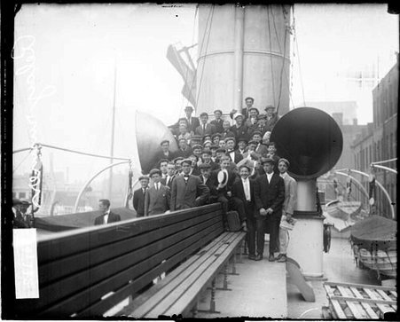 Group of relay runners wearing suits standing on the deck of a ship - Chicago Daily News, Inc.