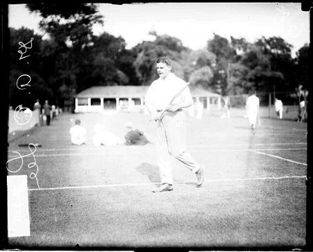 Tennis player Dr. A. O. Lee holding a tennis racket, walking on a tennis court at the Aztec Tennis Club - Chicago Daily News, Inc.