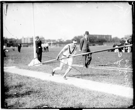 University of Chicago athlete Jacobs holding a pole used in pole vaulting, running on the athletic field - Chicago Daily News, Inc.