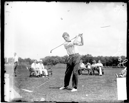Golfer E. T. Lazear holding a golf club over his shoulder, standing in a follow-through position - Chicago Daily News, Inc.