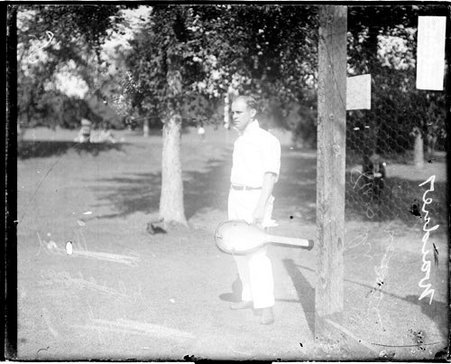 Tennis player L. H. Waidner carrying a tennis racket in a case, standing outdoors - Chicago Daily News, Inc.