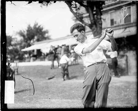 Golfer Dr. W. E. Code holding a golf club over his shoulder, standing in a follow-through position - Chicago Daily News, Inc.