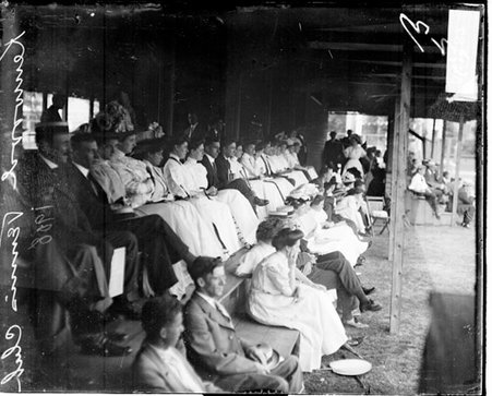 Spectators sitting on bleachers covered by a canopy at the Kenwood Tennis Club - Chicago Daily News, Inc.