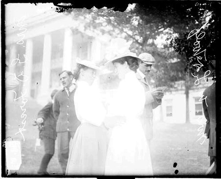 Golfers Mrs. W. L. De Wolf and Mrs. G. D. Forest standing on a sloped lawn in front of a building - Chicago Daily News, Inc.