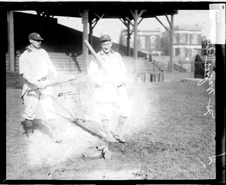 Baseball player Honus Wagner, Pittsburgh, and an unidentified teammate holding baseball bats, walking in front of grandstands - Chicago Daily News, Inc.
