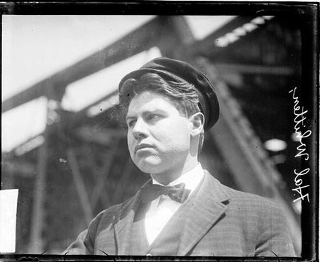 Hal Whitten looking to his right, standing outdoors in front of a structure wearing a sailing captain's hat - Chicago Daily News, Inc.