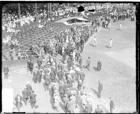 Crowds walking and standing on the field in front of field level seats and grandstands at West Side Grounds - Chicago Daily News, Inc.