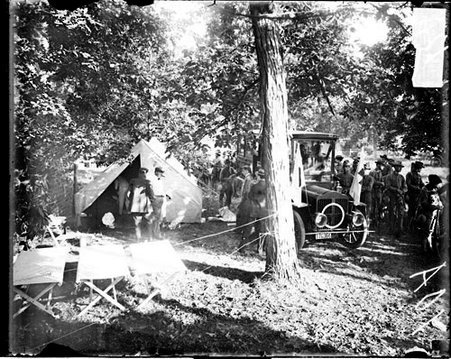 People standing in front of and in a tent set up amid trees during the Cobe Cup Race - Chicago Daily News, Inc.