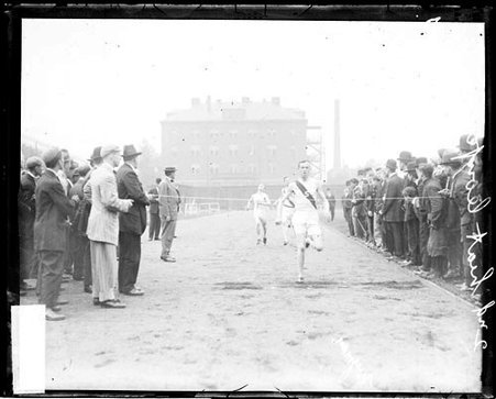 Athlete Wyman crossing the finish line during a race on the track at Marshall Field - Chicago Daily News, Inc.