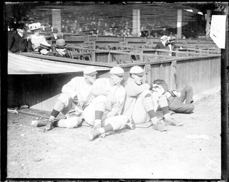 Baseball players George Wiltse, Merkle, and Art Fletcher, New York, sitting on the ground in front of field-level seats - Chicago Daily News, Inc.