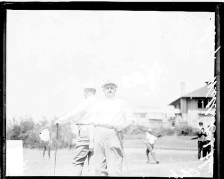 Golfer Willard, Secretarty, holding a golf club, standing on the grounds of the South Shore Country Club - Chicago Daily News, Inc.