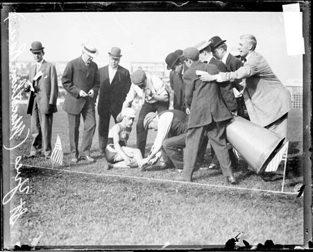 Runner St. Yves sitting on the ground on the field at South Side Park during a marathon - Chicago Daily News, Inc.