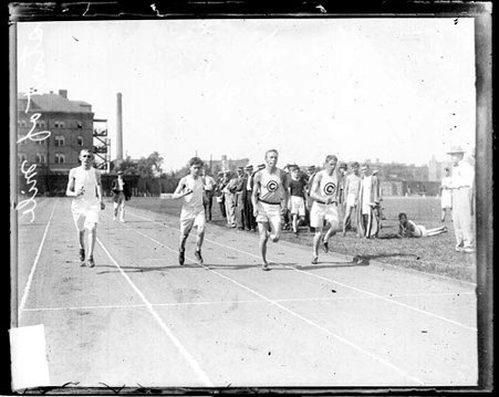 Athletes Taylor, Johnson, and two unidentified athletes running on the track at Marshall Field - Chicago Daily News, Inc.