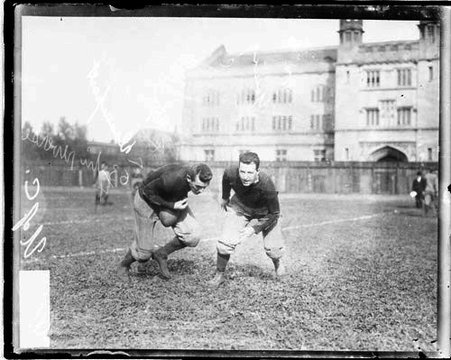 University of Chicago football players Davenport, holding a football, and Young running on the field at Marshall Field - Chicago Daily News, Inc.