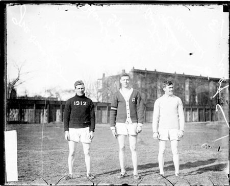 University of Chicago runners Harold Goettler, Ira Davenport, and Austin Menaul standing on a grass field - Chicago Daily News, Inc.