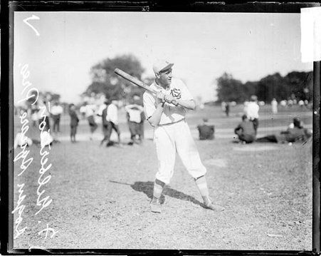 Logan Square Pres. baseball player F. Gilbertson holding a baseball bat, standing in a batting stance on a baseball field - Chicago Daily News, Inc.