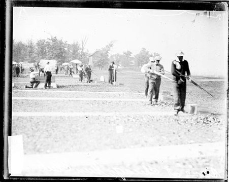 Shooters loading rifles that they are holding, standing in lanes on a shooting range at the Chicago Gun Club - Chicago Daily News, Inc.