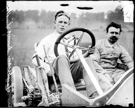 Automobile driver Scubrian sitting in the driver's seat of a Simplex automobile parked outdoors, during the Algonquin Hill Climbing Contest - Chicago Daily News, Inc.