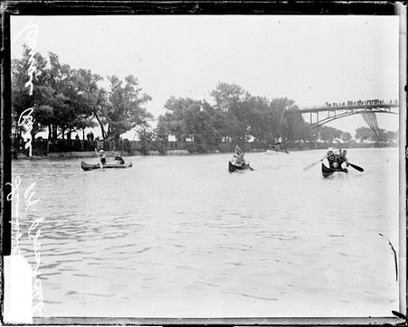Rowers racing in three canoes during a race involving the Lincoln Park Boat Club on a body of water in Lincoln Park - Chicago Daily News, Inc.