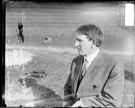Northwestern University coach Omer sitting in profile on a grass field - Chicago Daily News, Inc.