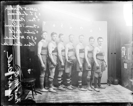 Members of the First M. E. basketball team standing in front of a light-colored backdrop in a room - Chicago Daily News, Inc.