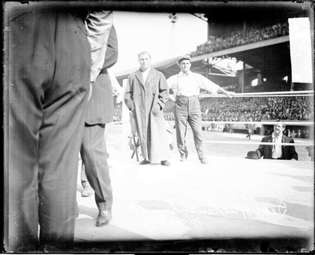 Wrestler George Hackenschmidt wearing a robe, standing in a wrestling ring on the field at Comiskey Park - Chicago Daily News, Inc.