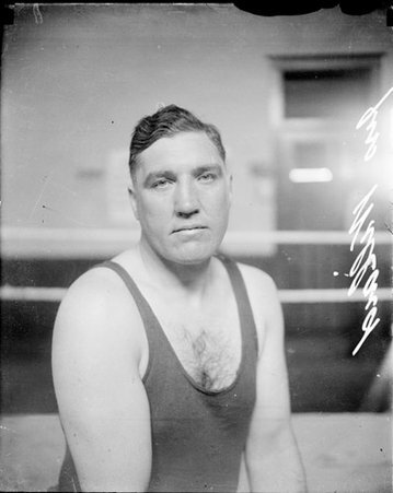 Boxer, J. Willard facing the camera, sitting in a boxing ring - Chicago Daily News, Inc.