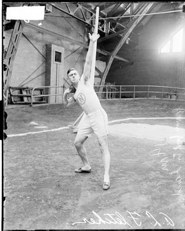 Athlete A. L. Fletcher athlete holding a shot put close to his shoulder in a gymansium - Chicago Daily News, Inc.