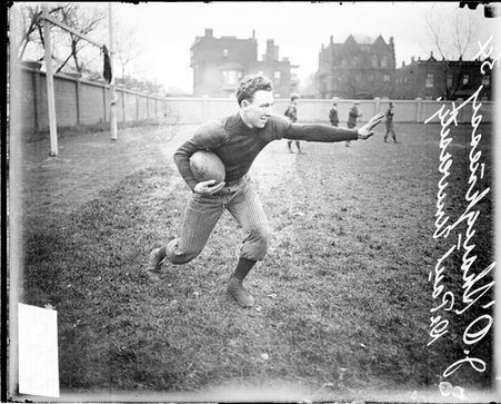 DePaul University football player J O'Shaughnessy holding a football on an athletic field - Chicago Daily News, Inc.