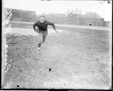 University of Chicago football player Rademacher holding a football, running towards the camera at Marshall Field - Chicago Daily News, Inc.