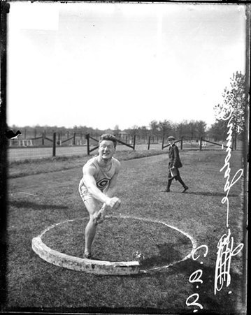 Chicago Athletic Association athlete Brundage following through after tossing a shot put on an athletic field - Chicago Daily News, Inc.