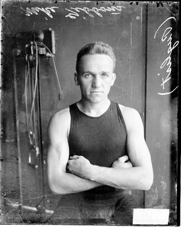 Boxer, Mike Gibbons standing in front of a dark-colored wall in a room - Chicago Daily News, Inc.