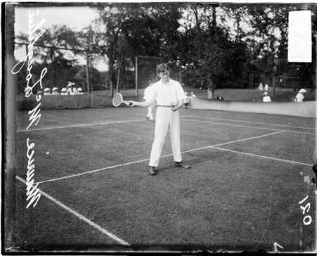 Tennis player McLoughlin holding a tennis racket with his right hand and drawing his right arm back - Chicago Daily News, Inc.